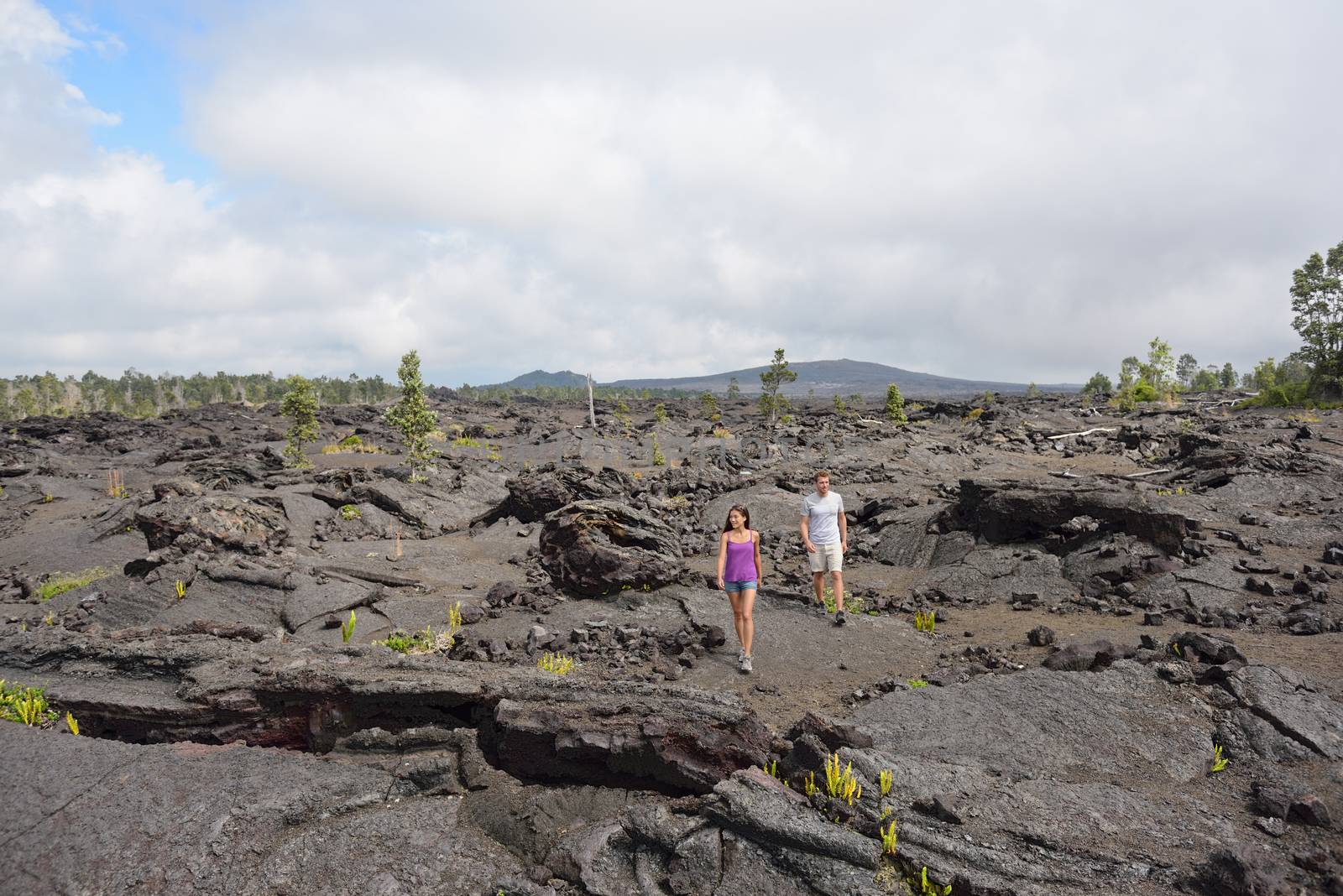 Hawaii destination travelers couple hiking in volcanic rocks on Kilauea volcano in Big island of Hawaii by Maridav