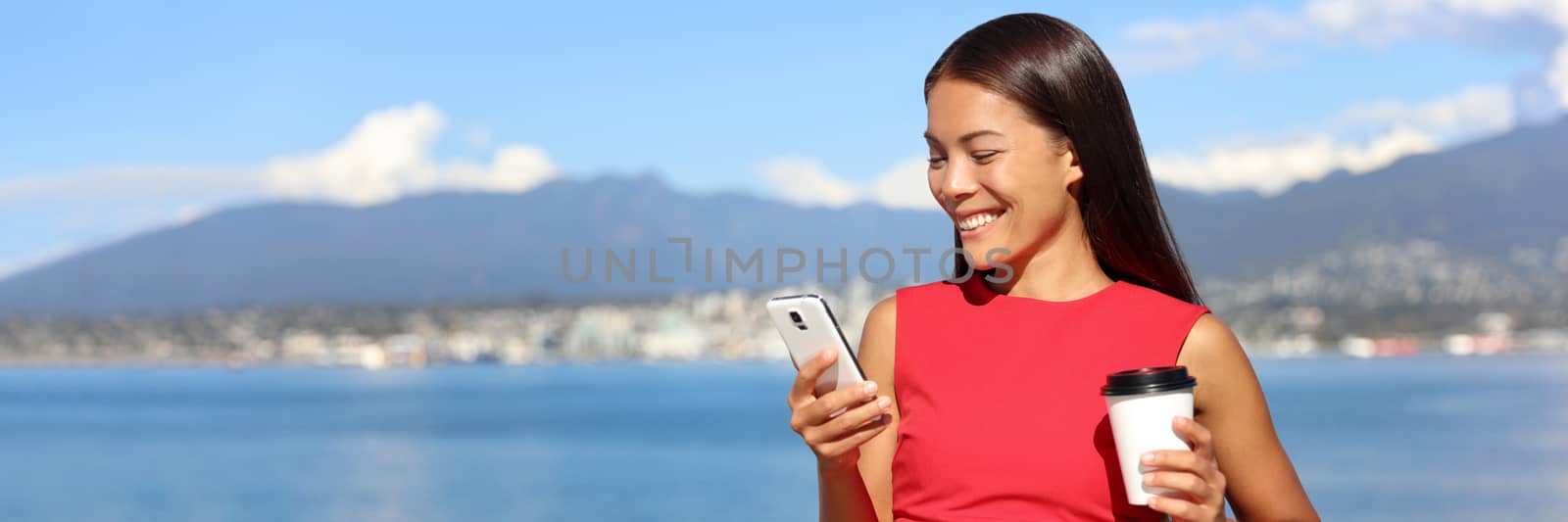 Banner crop for advertising copyspace, landscape of Vancouver in background. Businesswoman drinking coffee using mobile phone app to play video games online. Asian woman relaxing. Work lifestyle.