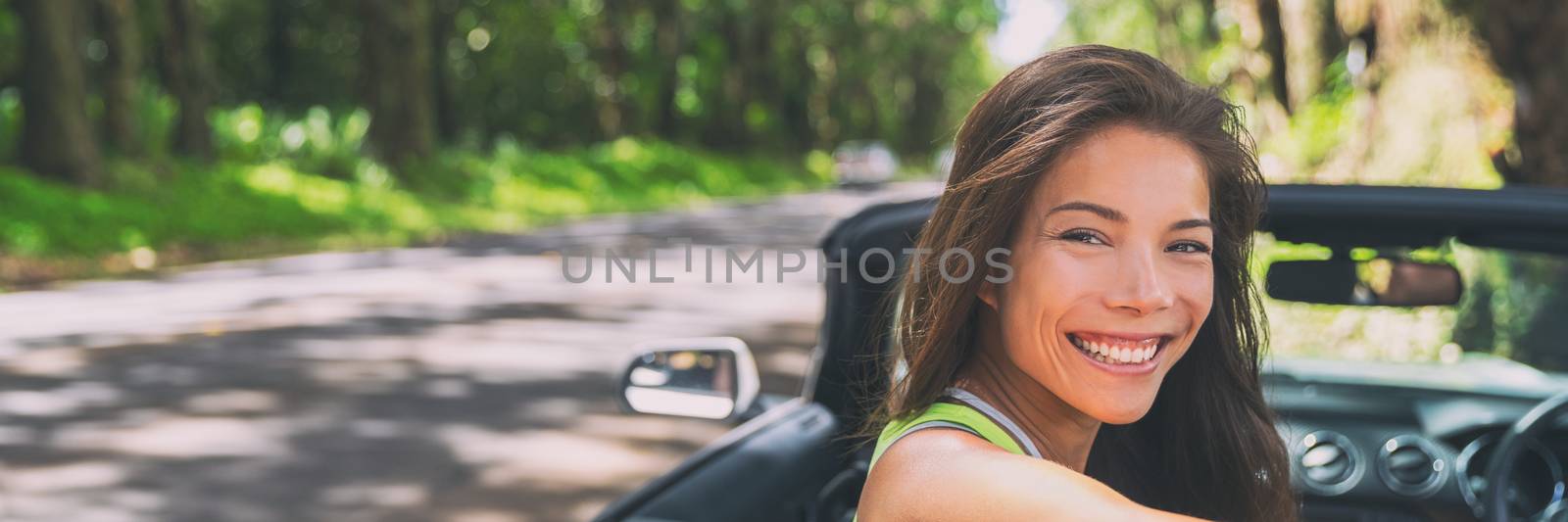 Asian car driver woman smiling happy relaxing in convertible car on summer road trip vacation. Travel destination driving through Hawaii, banner panorama.