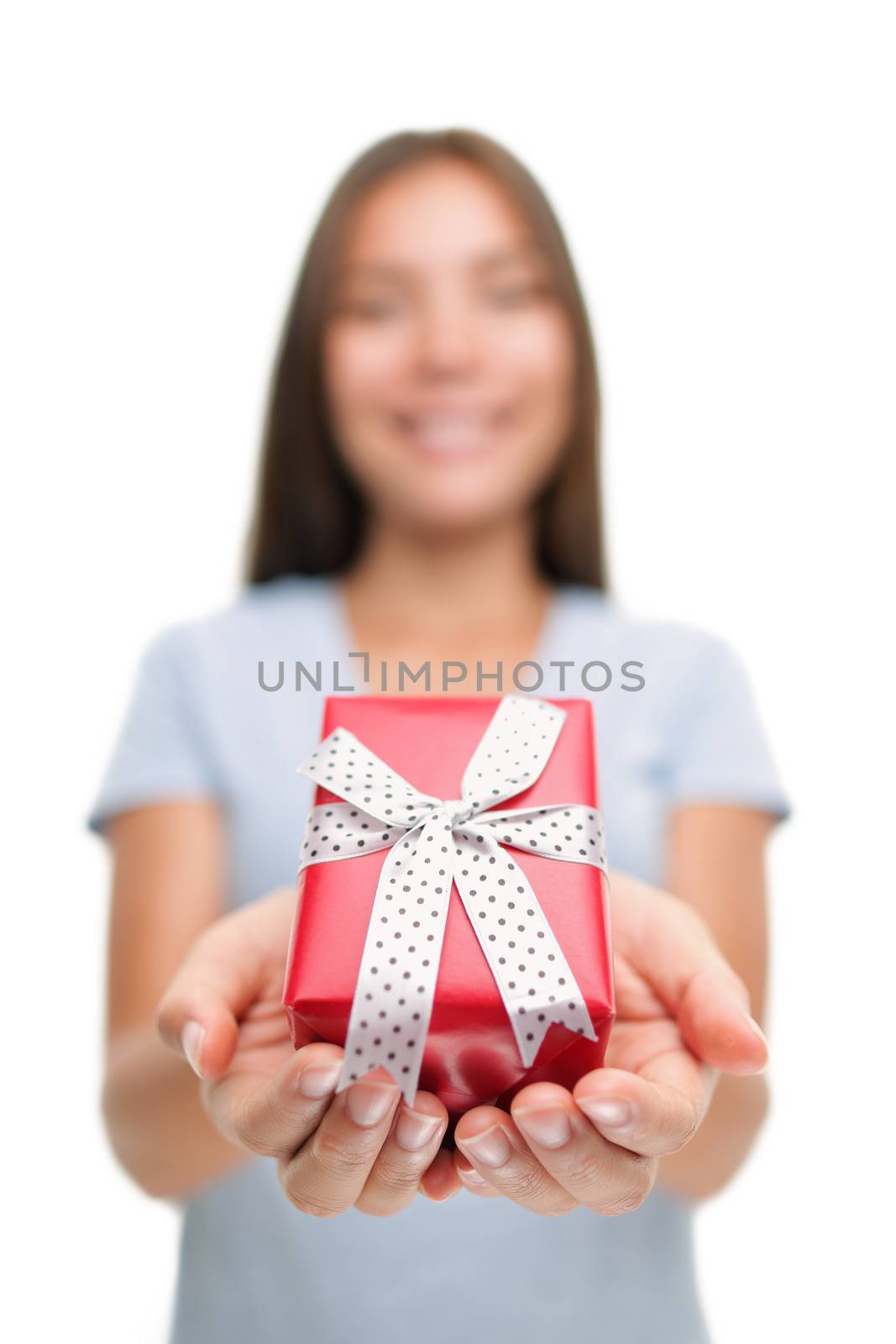 Woman giving red gift box as Christmas or birthday gifts isolated on white background. Holiday seasom shopping concept, lady presenting cute decorated package in studio by Maridav