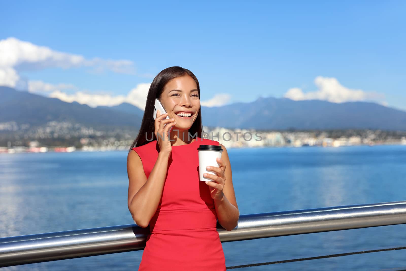 Happy business woman talking on the phone while drinking coffee outdoor in summer, landscape of Vancouver in background. Businesswoman work city lifestyle.