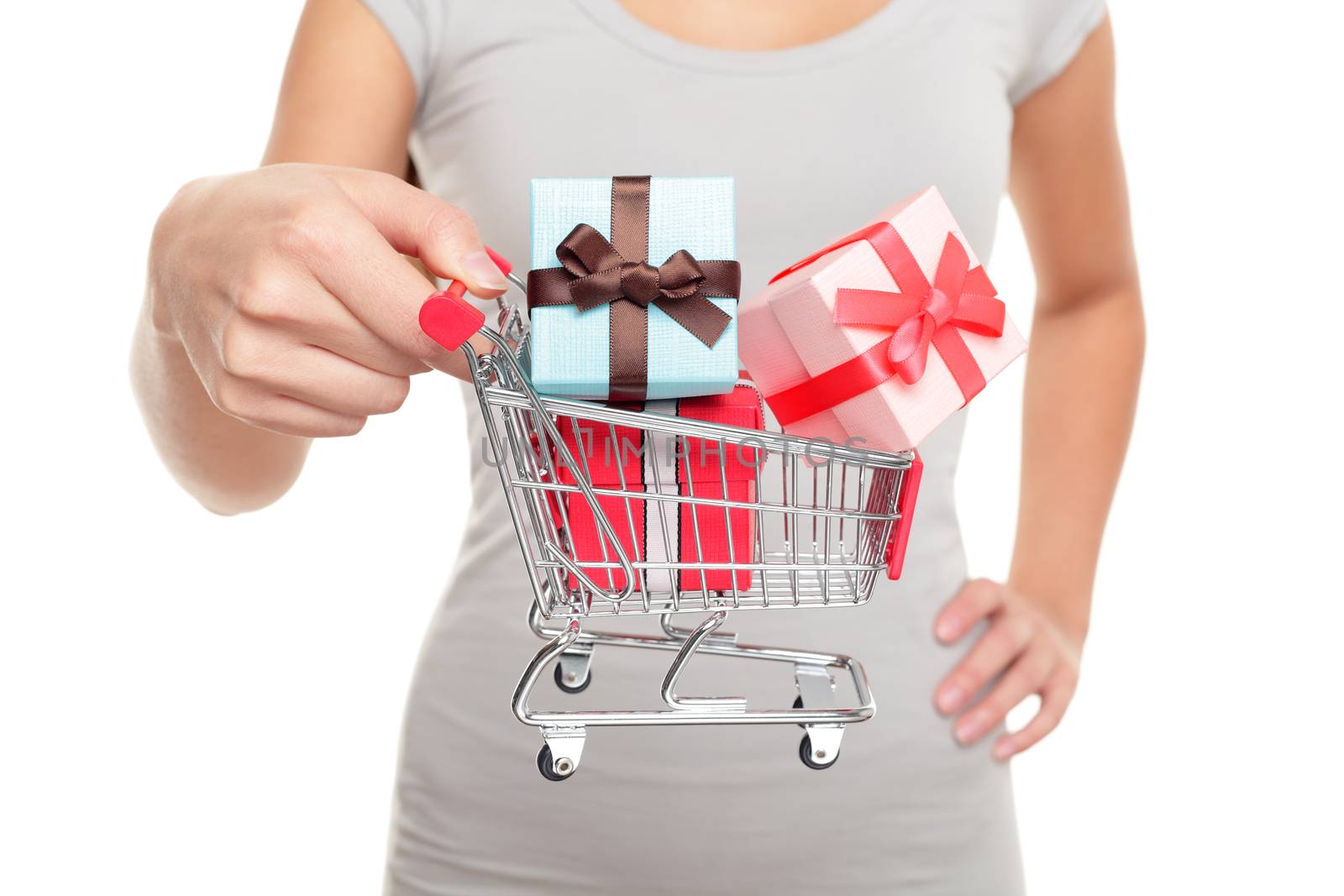 Miniature shopping cart with Christmas gifts for holiday shopping on boxing day or black friday. Closeup of woman hands holding mini toy object for spending concept.