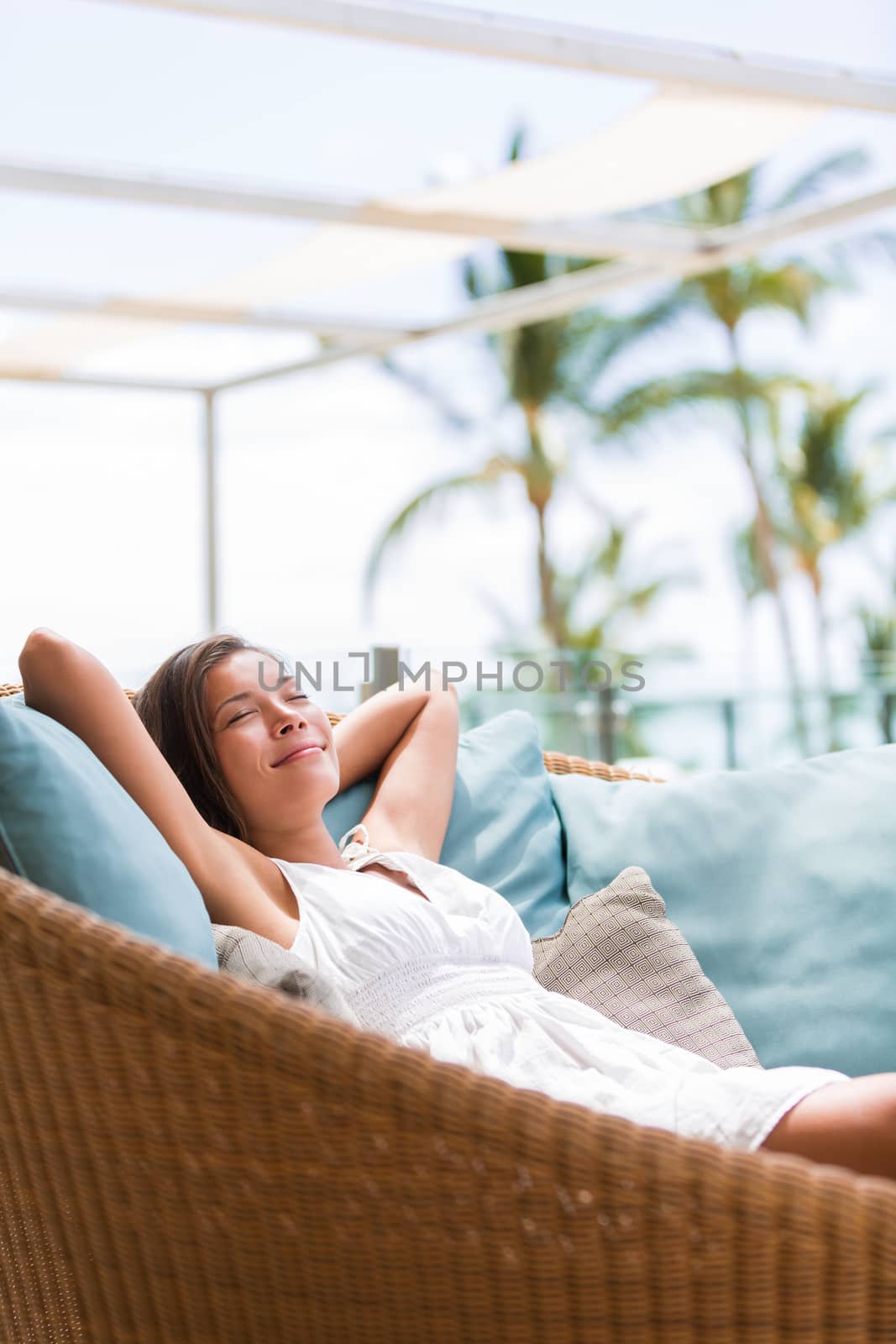 Luxury hotel lifestyle woman relaxing sleeping enjoying luxury sofa on outdoor patio living room. Happy lady lying down on comfortable pillows taking a nap for wellness and health by Maridav