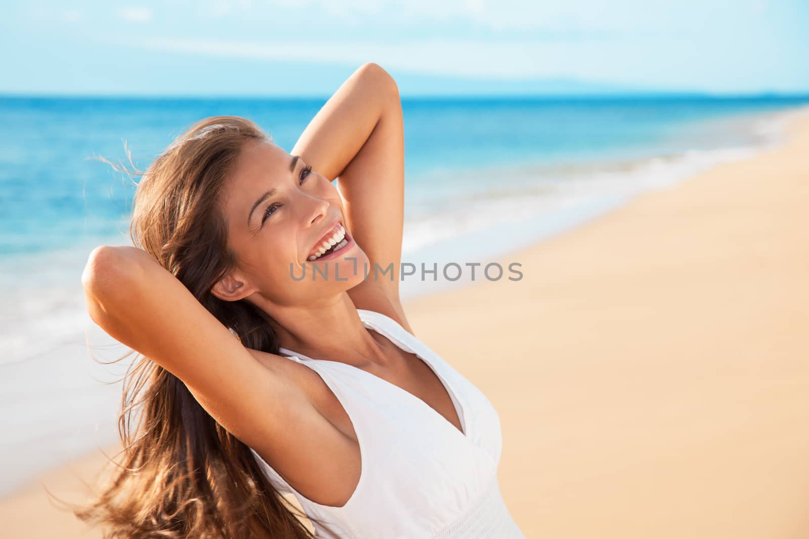 Smiling happy mixed race woman enjoying serene sunset. Carefree Asian woman relaxing on beach travel holidays vacation. Freedom and wellness concept.