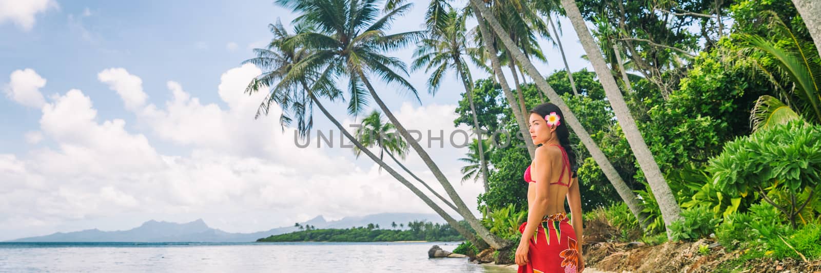 Tahiti luxury exotic travel vacation girl with polynesian flower walking on beach landscape with palm trees. Asian woman in red bikini and beachwear banner panorama.