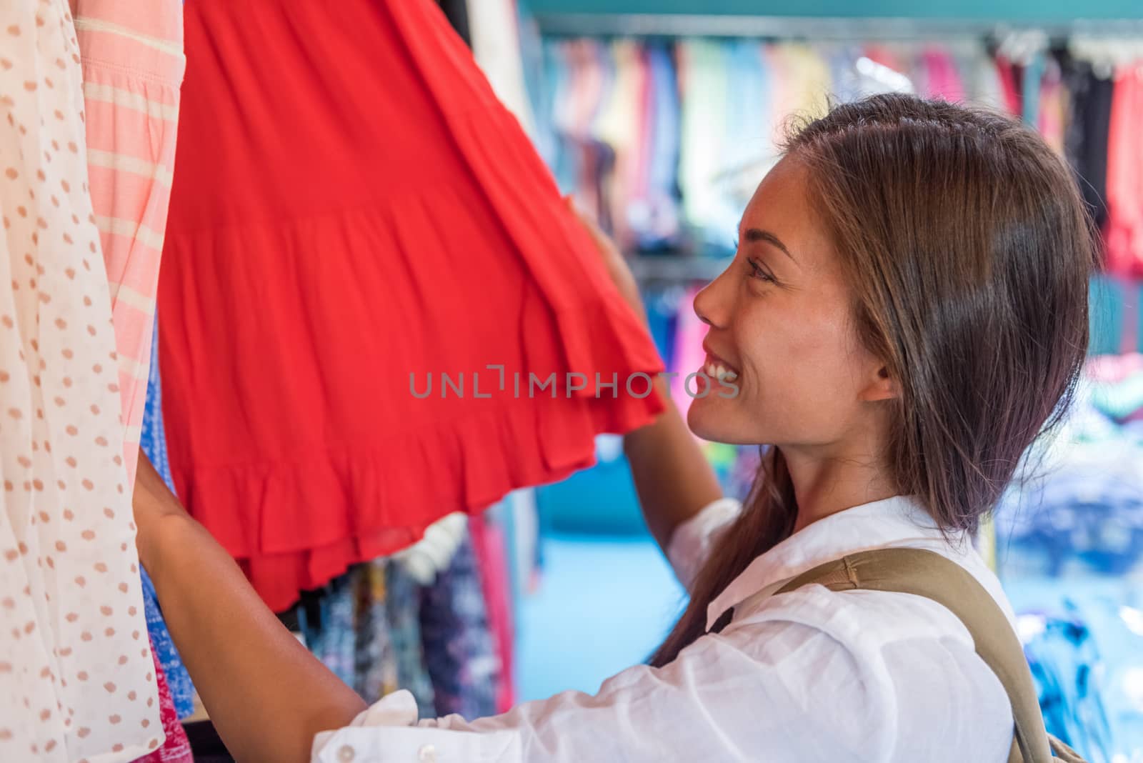 Asian young woman shopping new red dress at clothing store during travel tourism on summer vacation. Happy girl choosing outfit style.