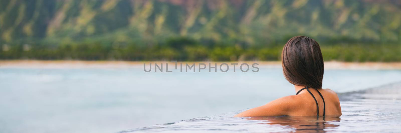 Luxury vacation woman travel tourist relaxing in infinity swimming pool on summer travel at tropical beach resort. girl alone on wellness spa relaxation outside in nature landscape banner panorama by Maridav