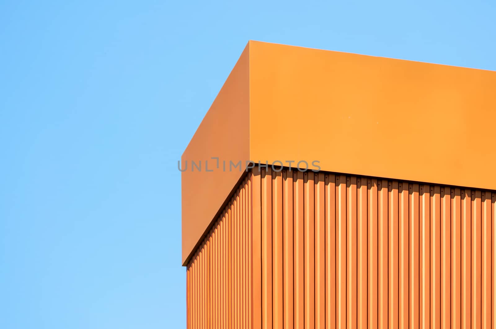 orange wall of a modern building on a background of blue sky simple architectural abstract background pattern