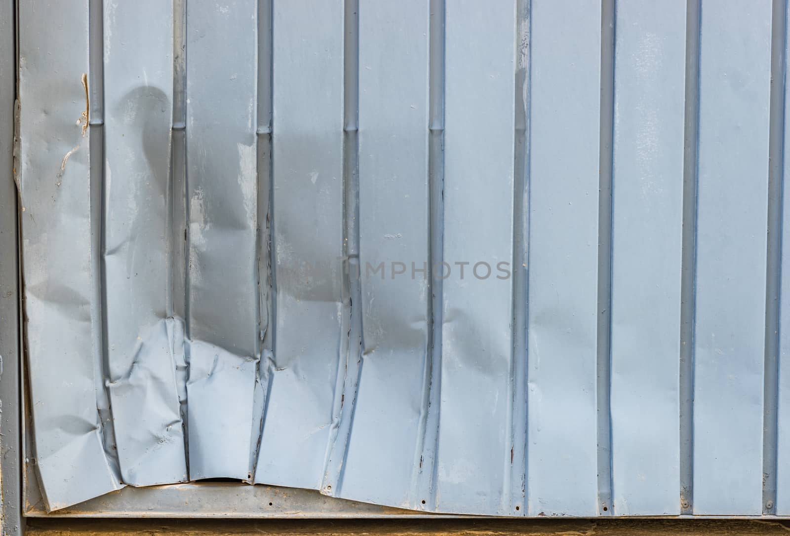 Close-up of dented gray garage metal door