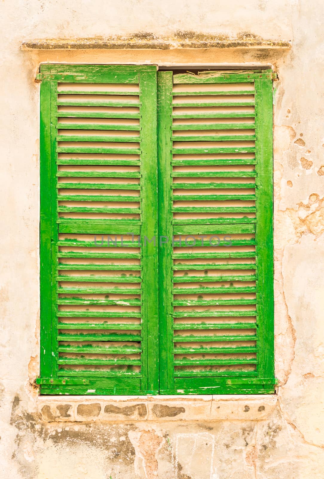 Detail view of closed old green wooden window shutters and wall
