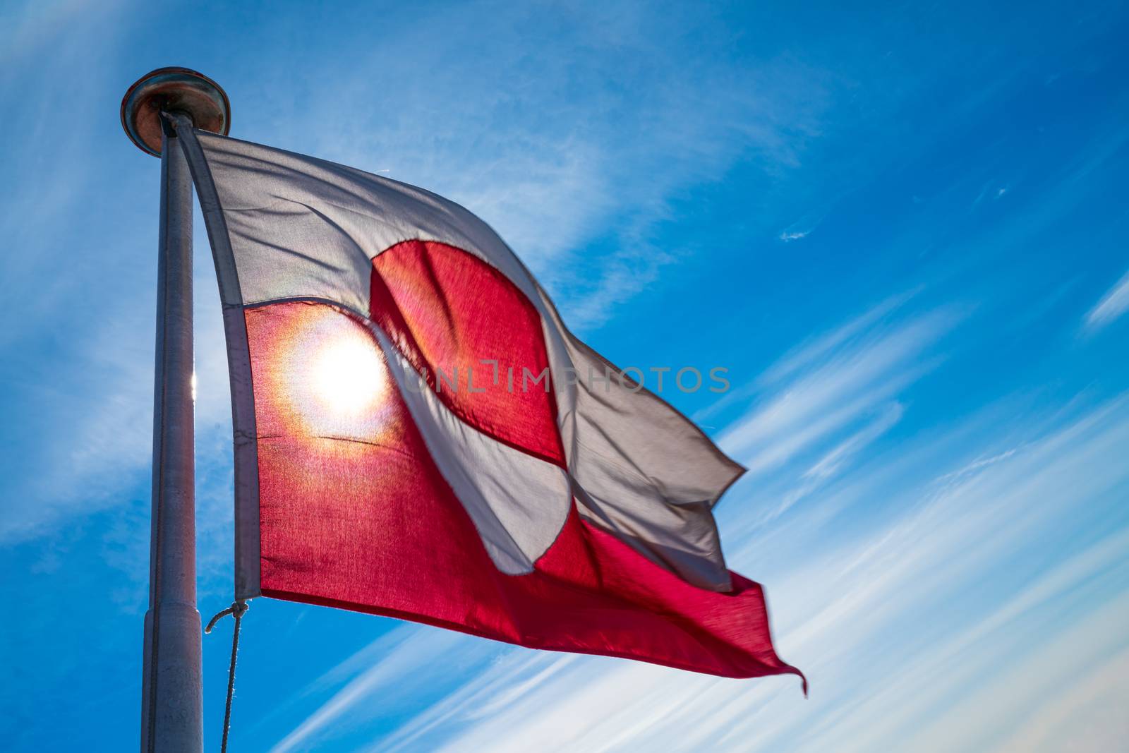 Greenland flag - Greenlandic flag against blue sky. Shot on Greenland on summer day. The National Flag of Greenland.