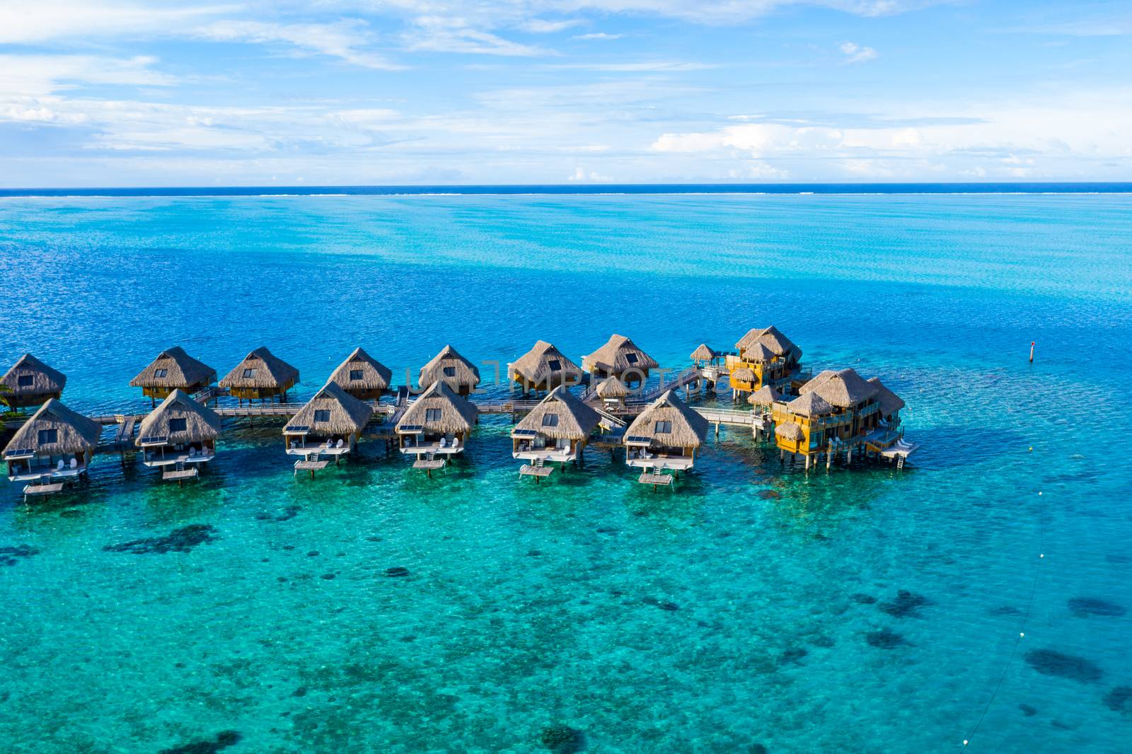 Travel vacation paradise aerial drone video with overwater bungalows in coral reef lagoon sea. Aerial video from Bora Bora, French Polynesia, Tahiti, South Pacific Ocean.