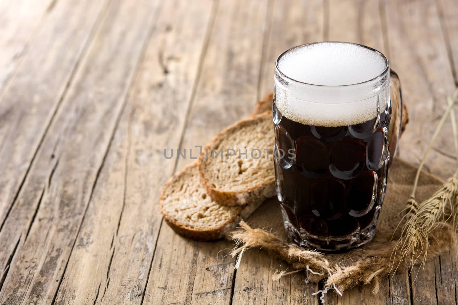 Traditional kvass beer mug with rye bread on wooden table