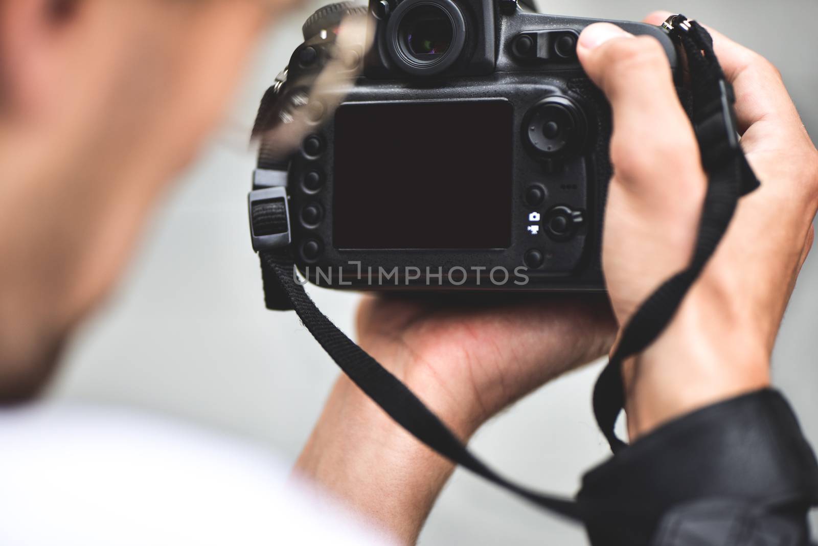 Digital single-lens reflex camera in hands. Photographer shooting hands close up. Man photographer makes photos for stock photography. Male hands hold the camera close-up