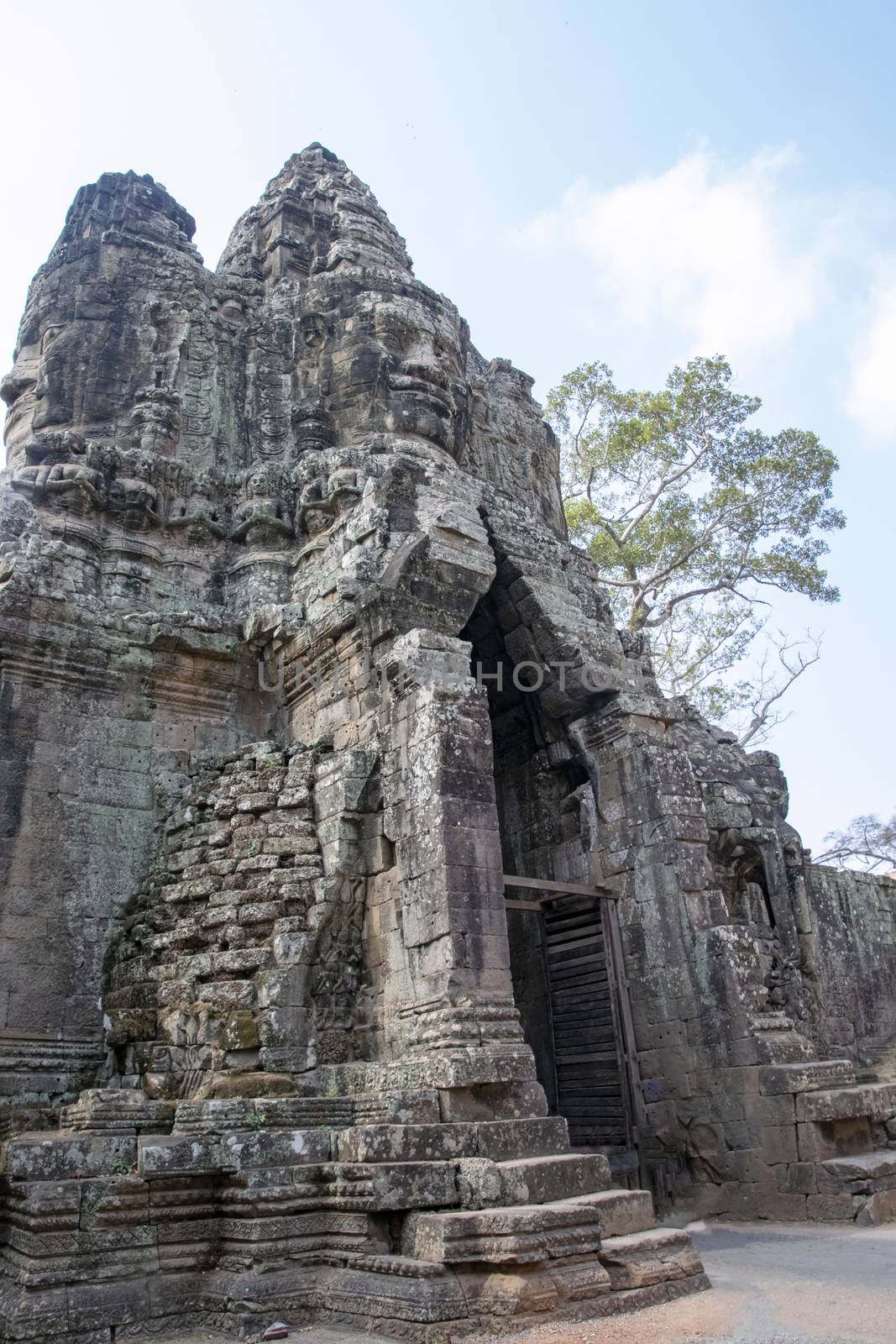 Cambodia, Bayon Temple - March 2016: The temple bridge is a main through road for traffic. Carved like the Bayon temple with a multitude of serene and smiling stone faces 