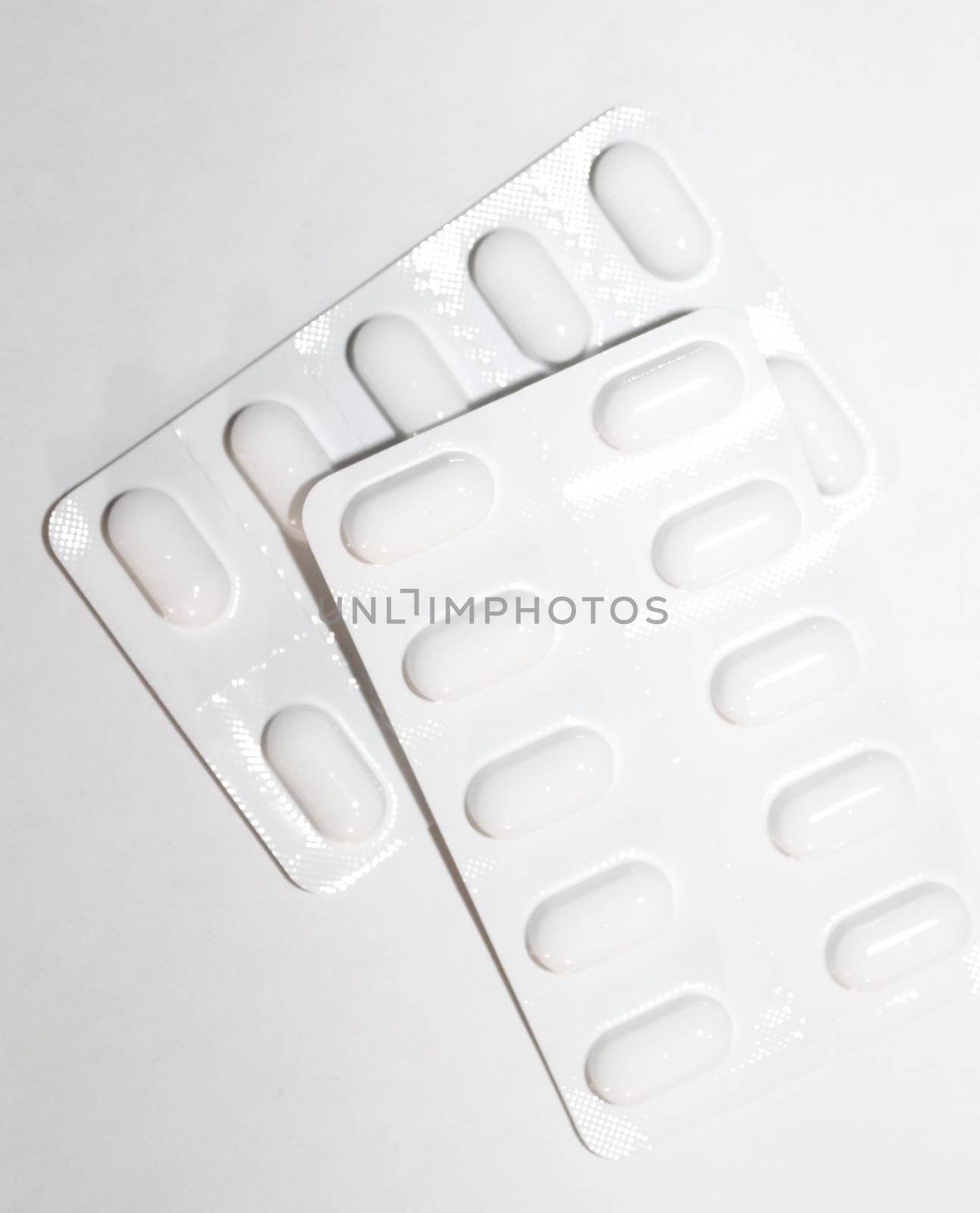 Packs of white pills packed in blisters with copy space isolated on a white background. Focus on foreground, soft bokeh. Pharmacy drugstore concept.