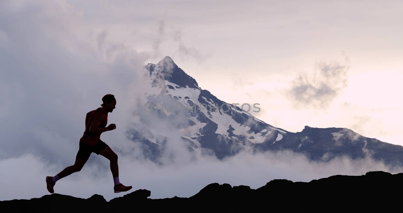 Running man athlete trail running in mountain. Male runner on run training outdoors active fit lifestyle.