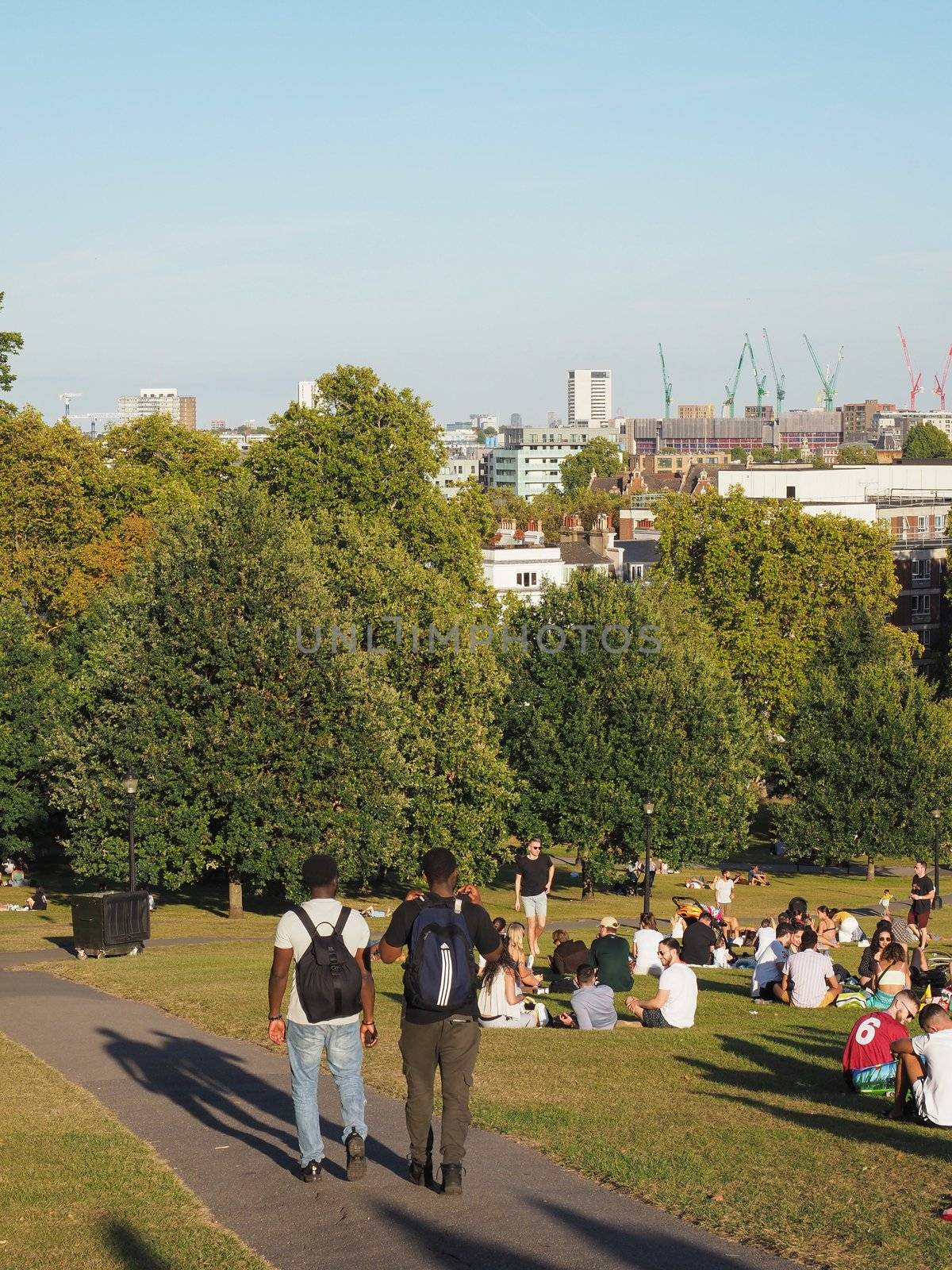 LONDON, UK - CIRCA SEPTEMBER 2019: People at Primrose Hill north of Regent's Park looking at London skyline at sunset