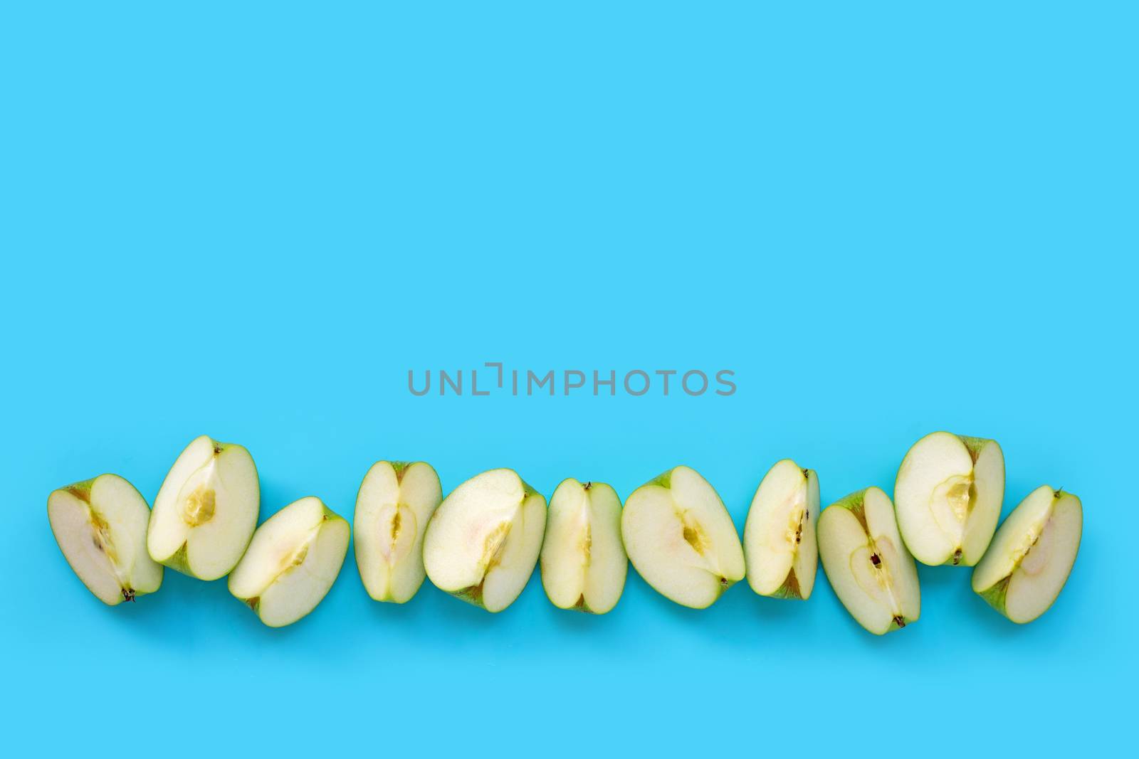 Green apple slices on blue background. Copy space