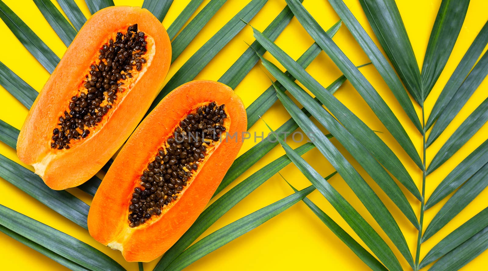 Sweet ripe papaya on tropical palm leaves. Top view