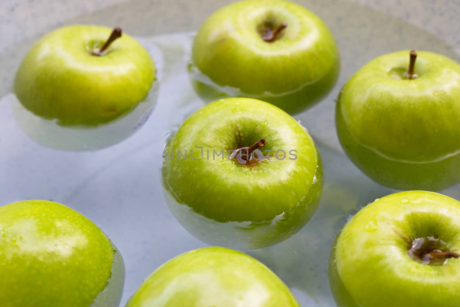 Soak fresh green apples in water. Washing fruit concept