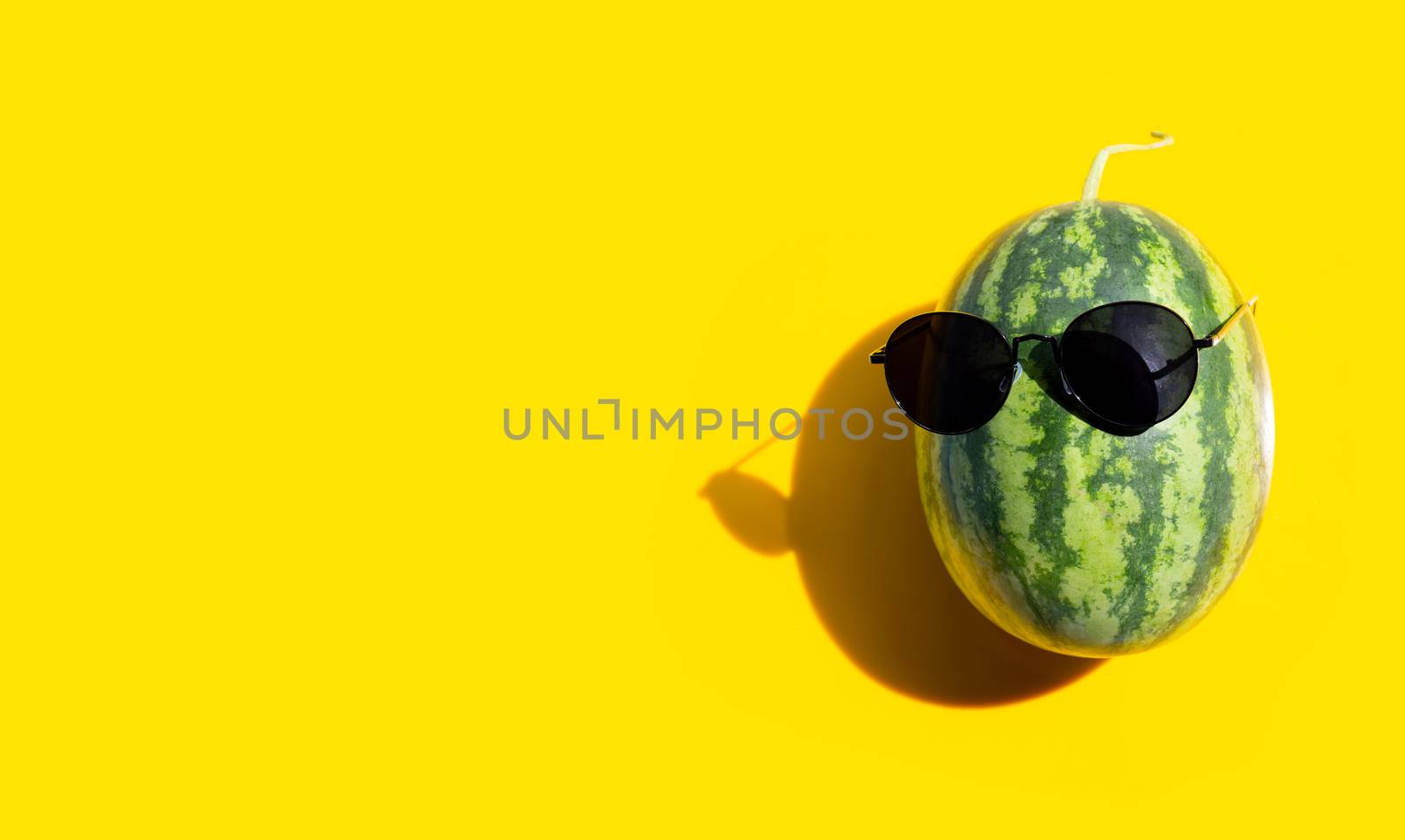 Watermelon with sunglasses on yellow background. Enjoy summer holiday concept. Copy space