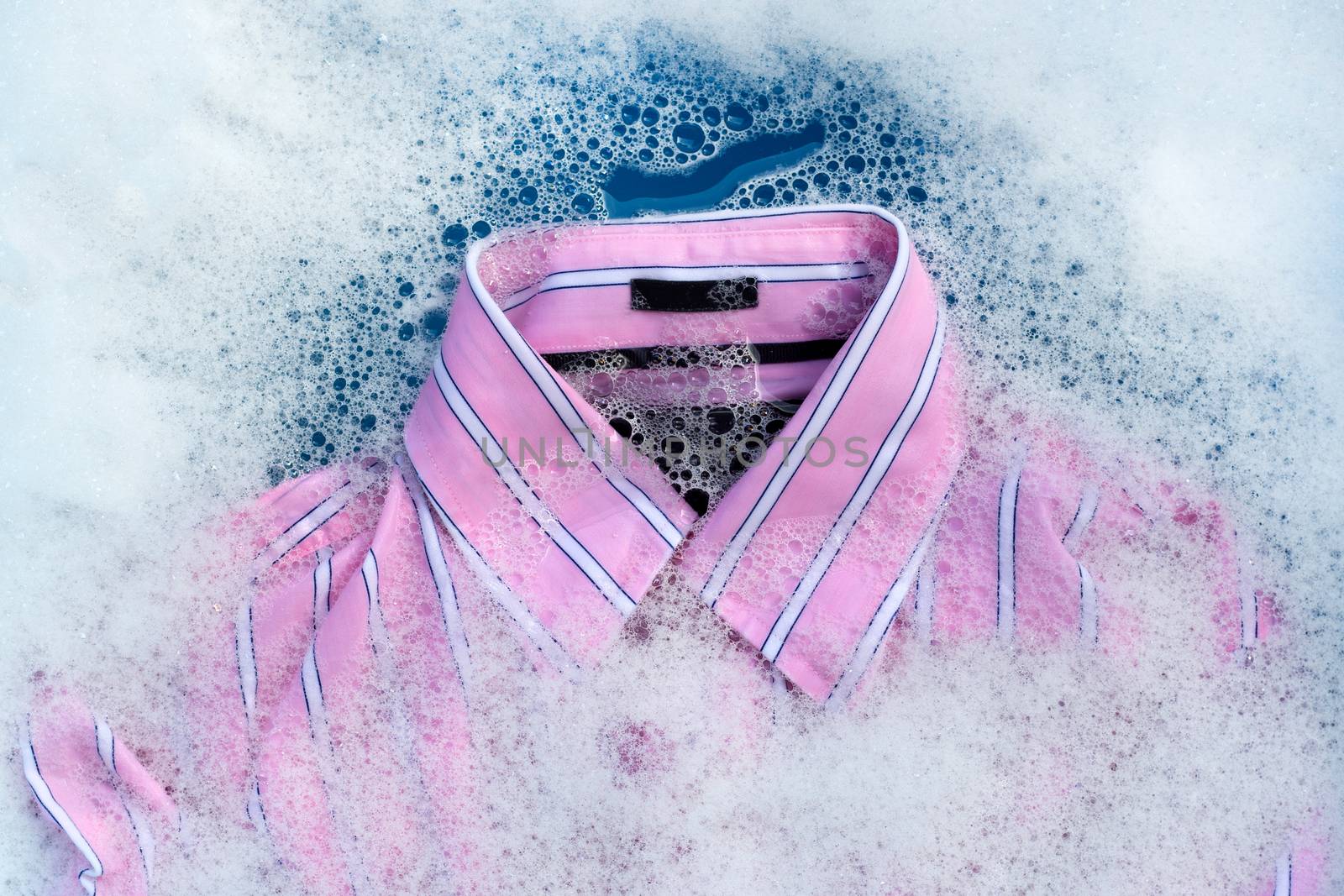 Pink shirt soak in powder detergent water dissolution, washing cloth. Laundry concept