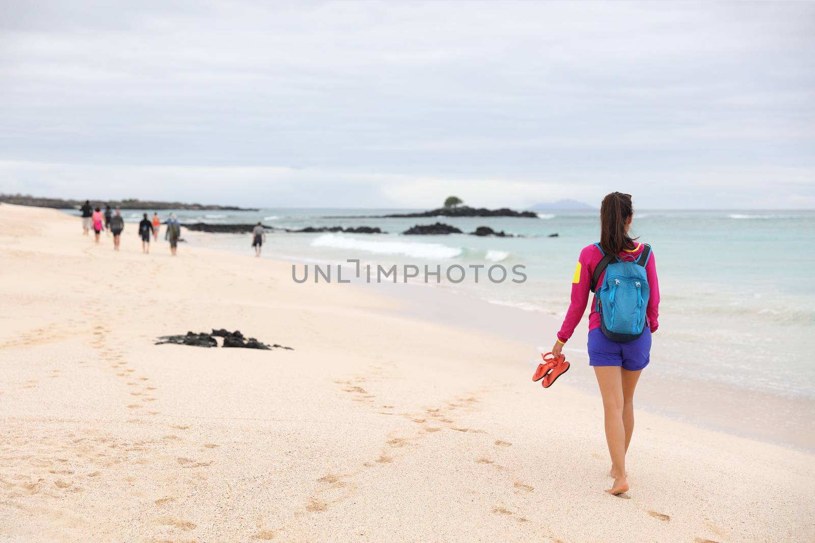 Galapagos Islands - woman on cruise ship tour visiting Playa las Bachas Beach on Santa Cruz Island. Woman walking barefoot in sand enjoying pristine nature landscape ecotourism