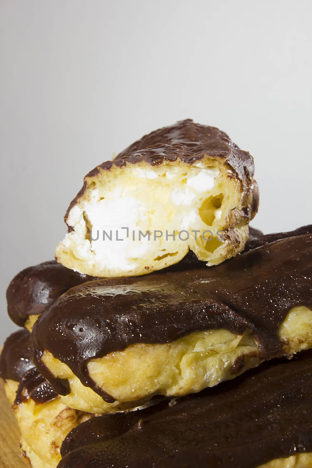 Eclairs with chocolate icing on a wooden table