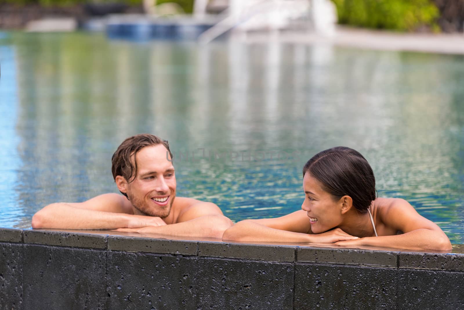 Wellness spa pool couple relaxing in hydrotherapy luxury travel resort on tropical holidays together enjoying the swim in water.