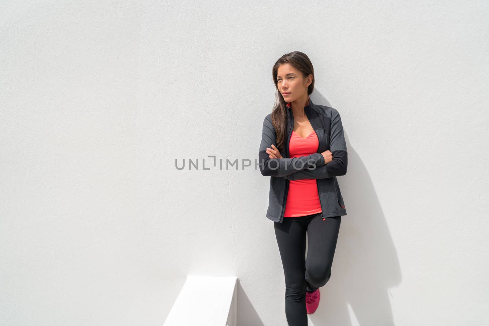 Activewear Asian girl model woman leaning on wall in yoga leggings and running jacket ready to train at gym. Active lifestyle healthy people by Maridav