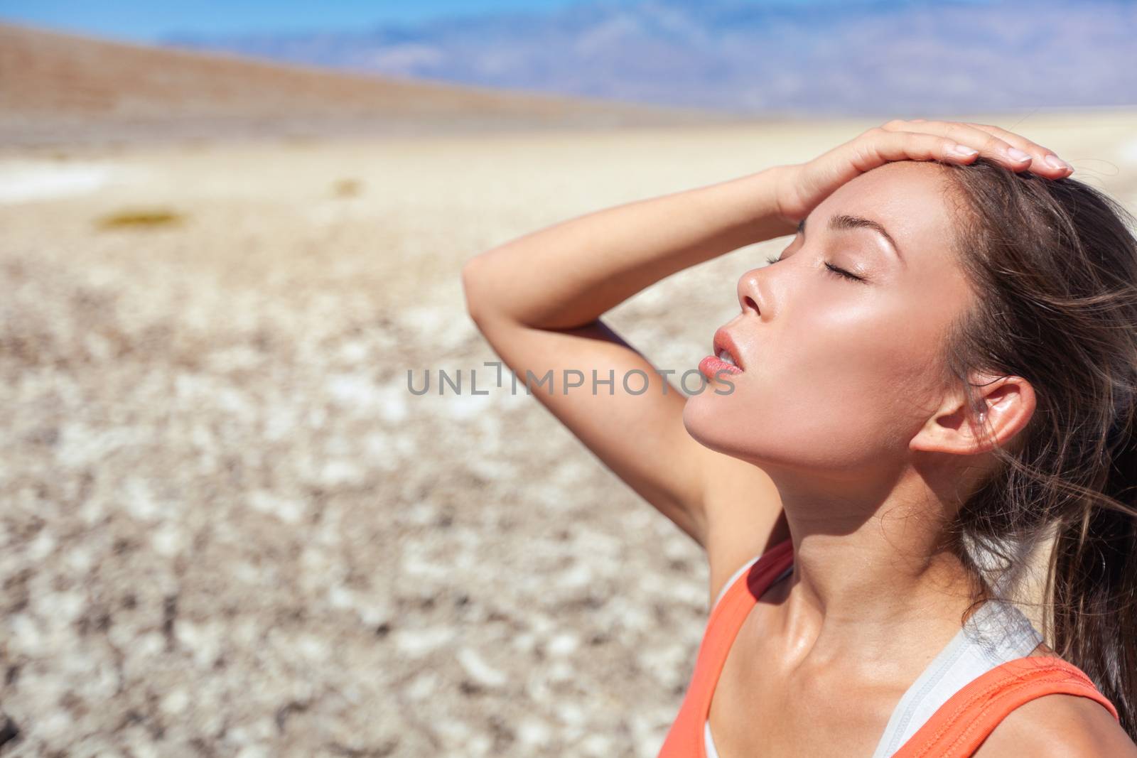 Heat stroke tired dehydrated girl under the desert sun hot temperature summer weather danger. Asian woman sweating exhausted.