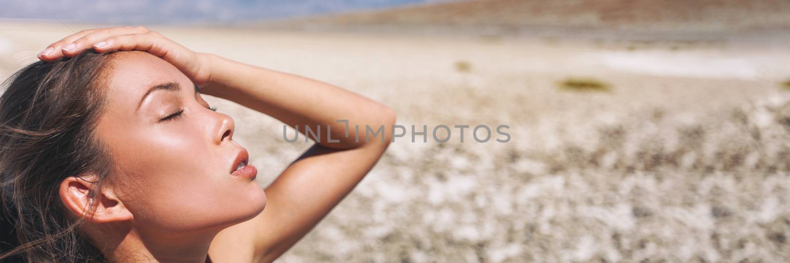 Heat stroke dehydrated girl in the desert sun hot temperature summer weather danger. Panoramic banner landscape with Asian woman tired sweating exhausted.