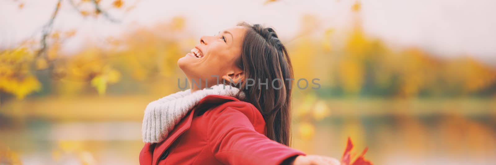 Autumn woman happy smiling feeling free in fall nature. foliage yellow colors of nature. Asian girl by the lake panoramic banner landscape. by Maridav