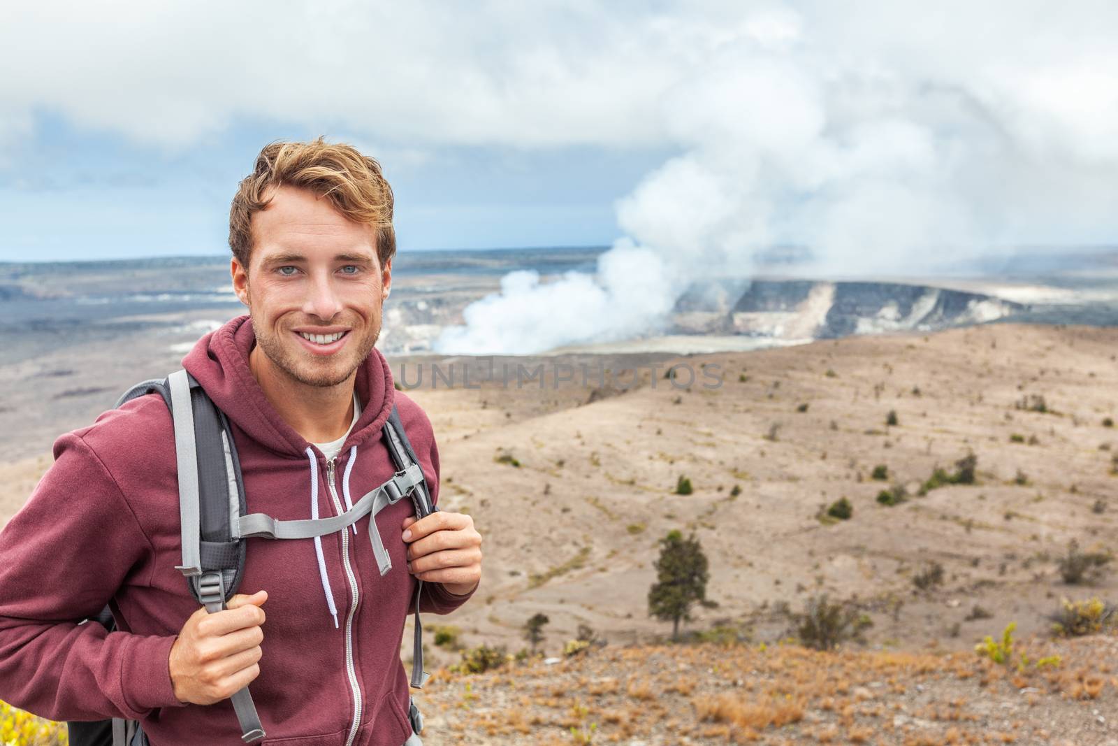 Hawaii volcano tourist man at Halemaumau crater in Kilauea caldera in Hawaii Volcanoes National Park, big Island with volcanic clouds and ash from eruption.