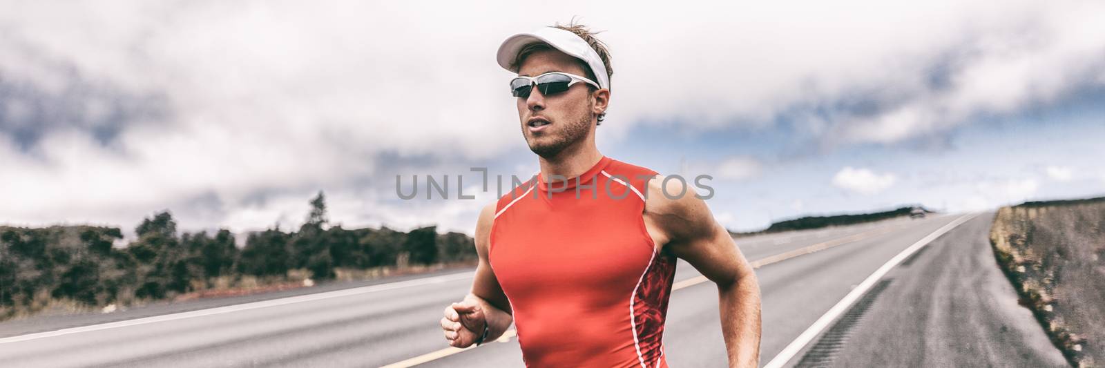 Triathlon runner man running on road panoramic backbround. Fit athlete jogging on competition race. Triathlete training for marathon banner panorama. by Maridav