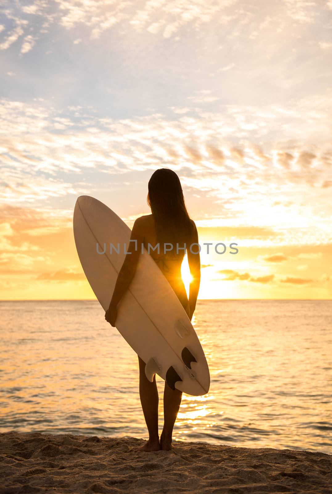 Beach sunset sexy surfer woman surfing lifestyle relaxing holding surfboard looking at ocean for surf. Active healthy living silhouette of sports athlete standing waiting for waves by Maridav