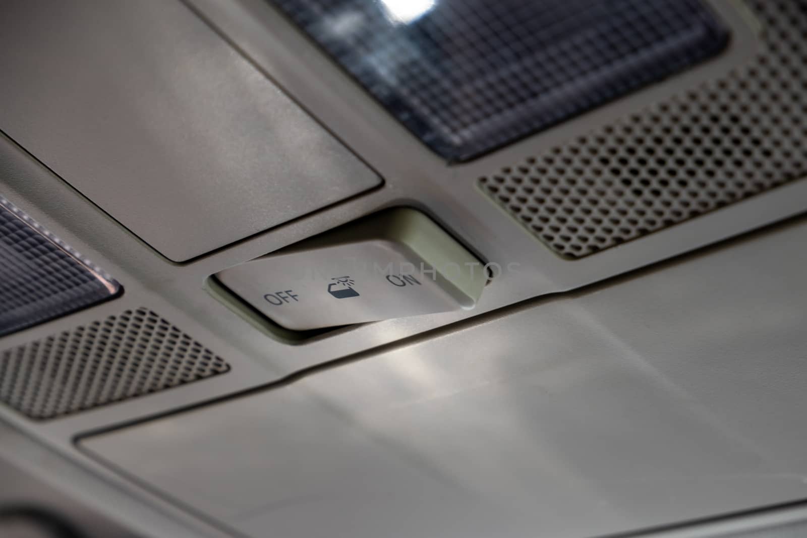 A switch on the roof of a car controlling the behavior of the interior lighting is switched to the "off" position.