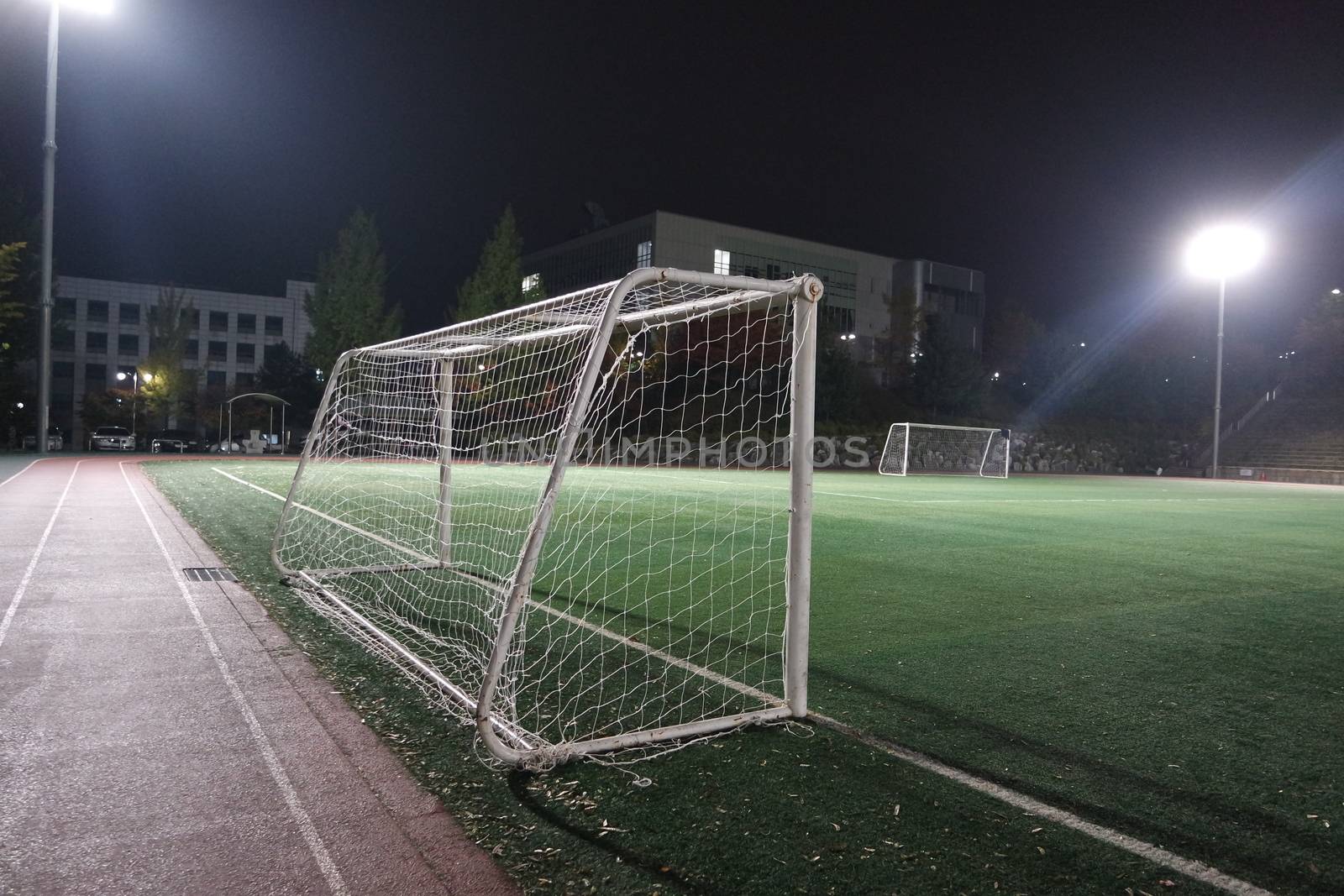 Night view of a soccer goal net under flood lights. Closeup view of goal net in a soccer playground