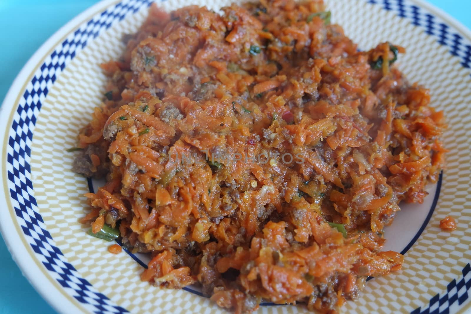 Top closeup view of a homemade dish made from carrot and vegetables served in a ceramic plate.