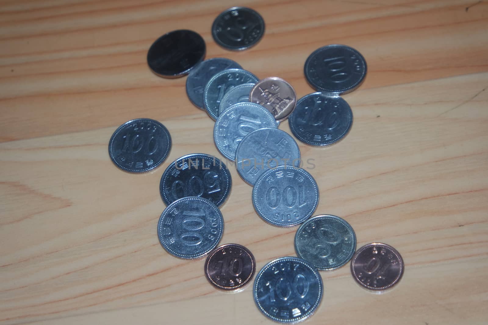 Korean won coin scattered over a wooden floor by Photochowk