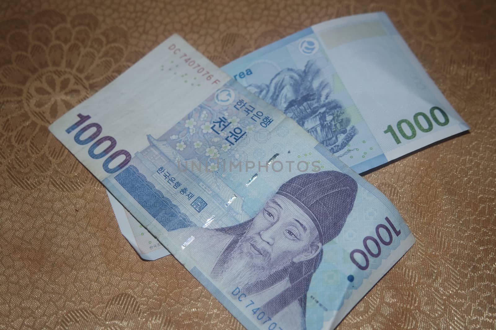 Korean won notes scattered over a wooden floor by Photochowk