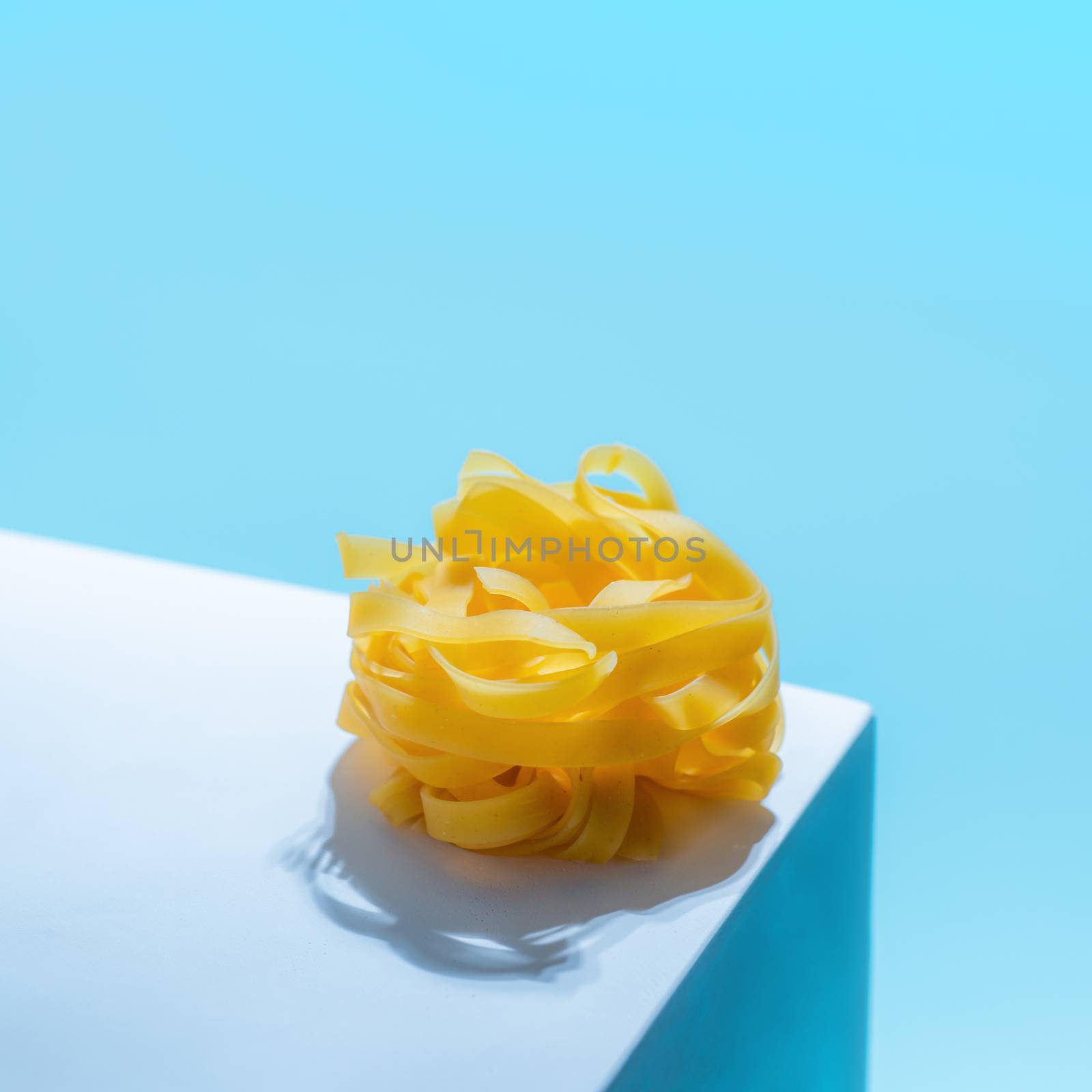 Pasta art with tagliatelle on blue background by fascinadora