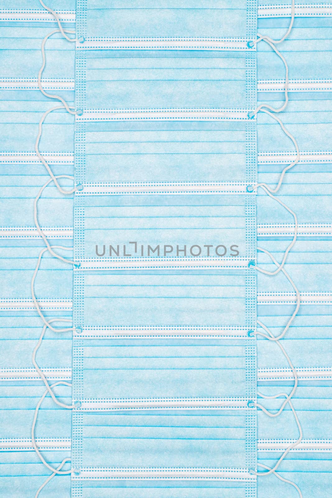 Background of medical face masks. Close-up view of lot blue disposable surgical respiratory bandage for human face with rubber ear straps as abstract medicine backdrop. Large group of objects.