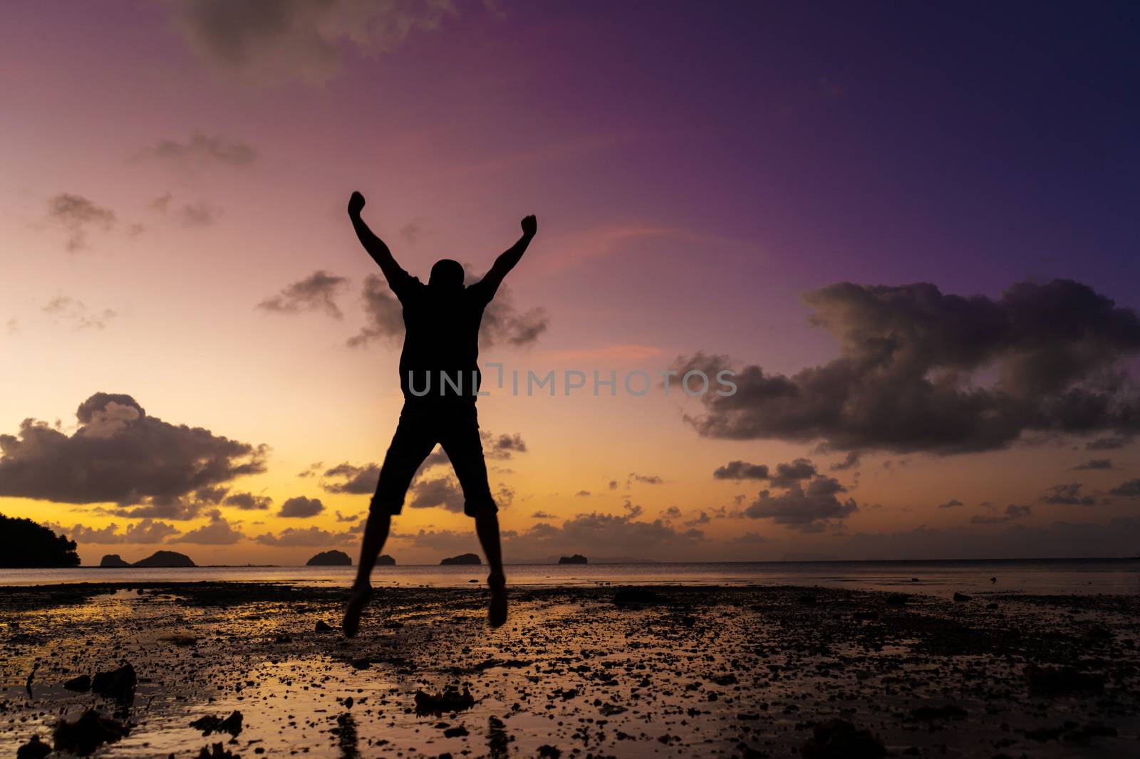 Silhouette of a man on the beach at sunset. Man rejoices meets the sunset.