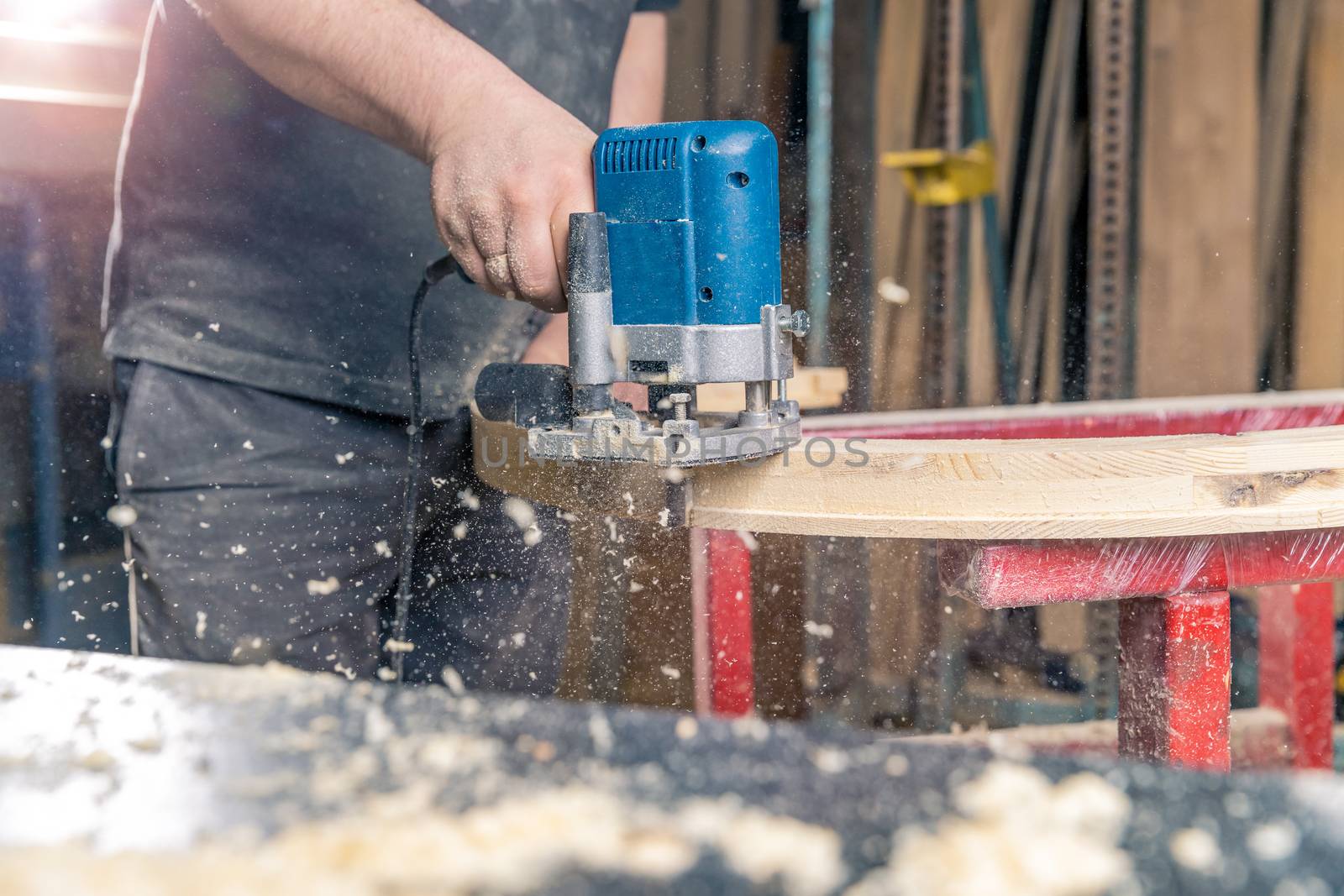 milling round wooden window by hand electric cutter in joinery.