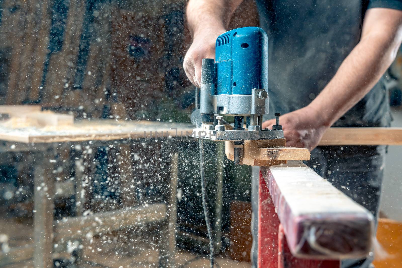 Milling wood in the joinery using manual mechanical cutters. Flying sawdust in the air. Copy space.