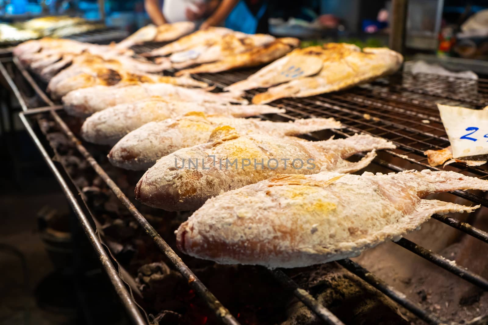 Asian food. Counter with fish in salt on the grill at a night food street market. by Try_my_best