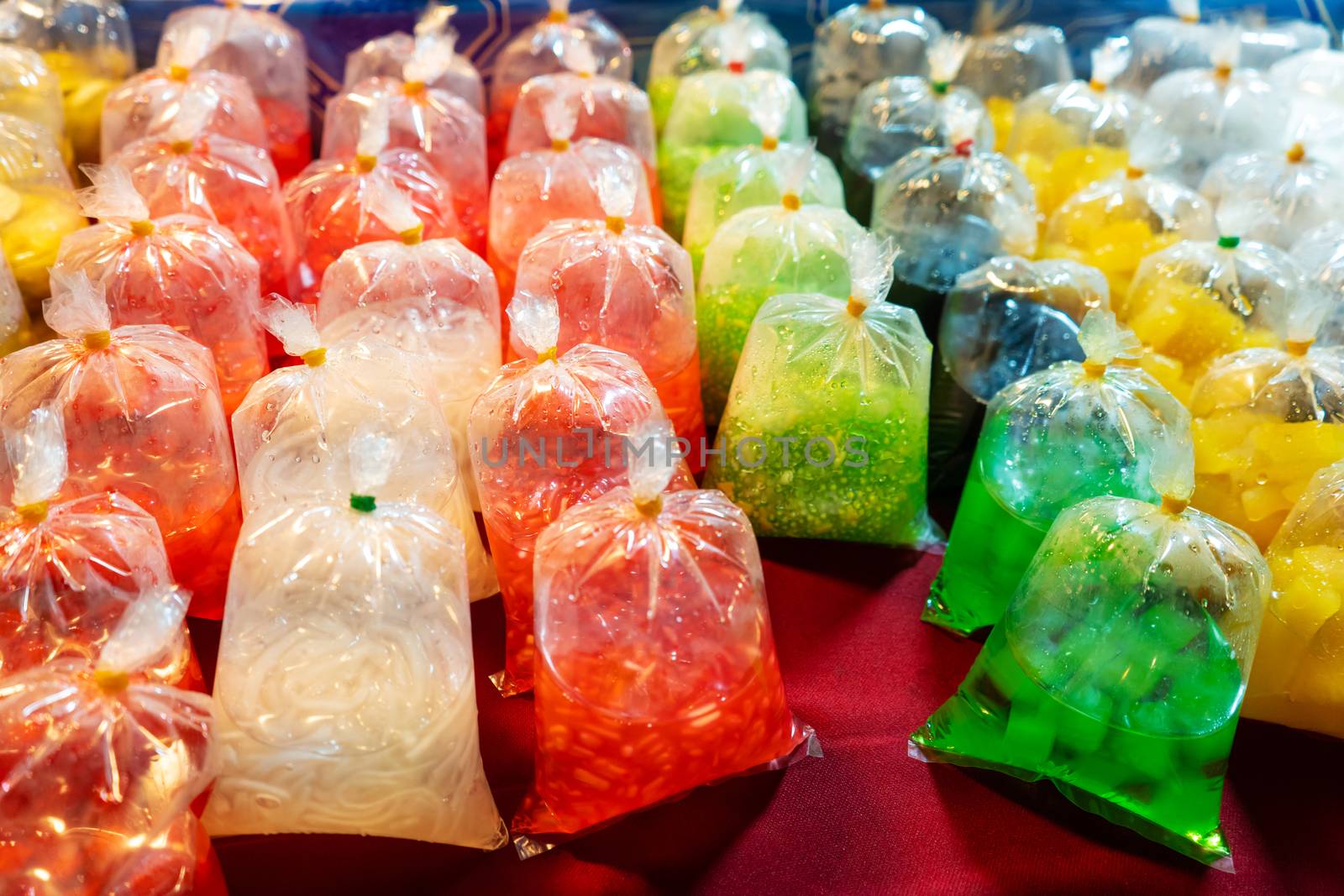 Colored desserts in plastic bags at a street food market in Asia. Unusual Asian food