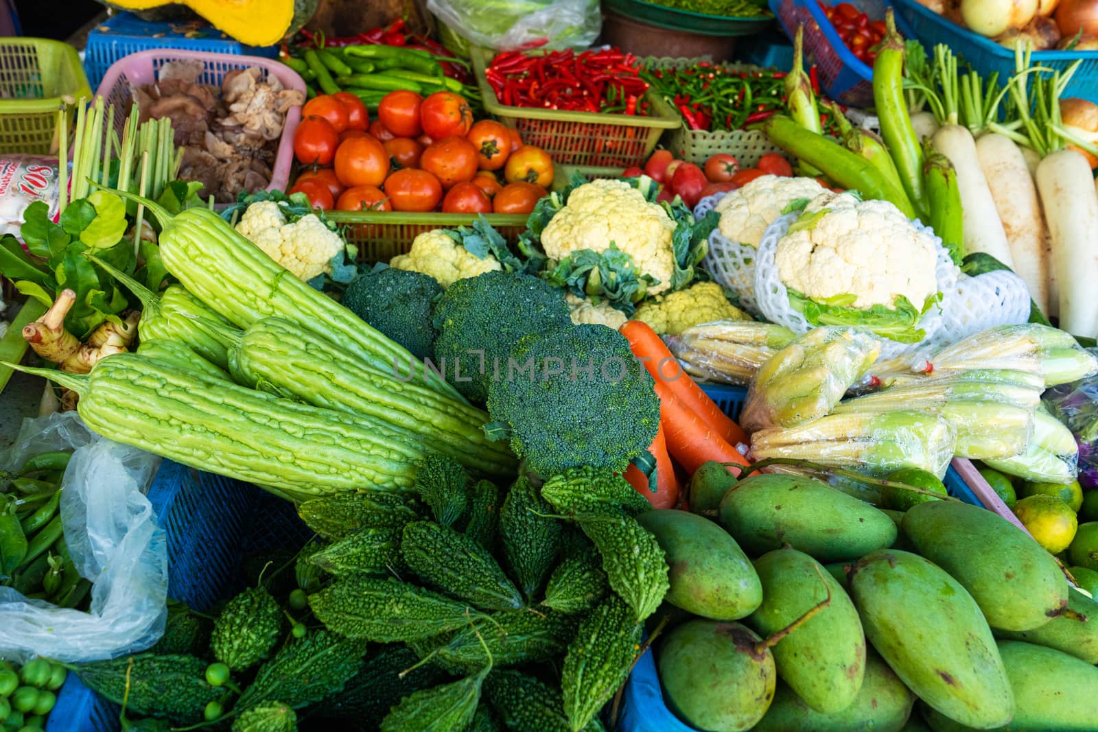 Fresh vegetables, fruits and greens on a counter in a street market.